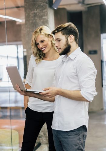 Coworkers in a modern office Cowerkers looking at notebook in a modern office